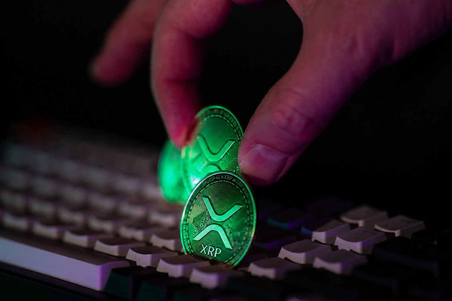 Hands placing illuminated cryptocurrency coins on a keyboard